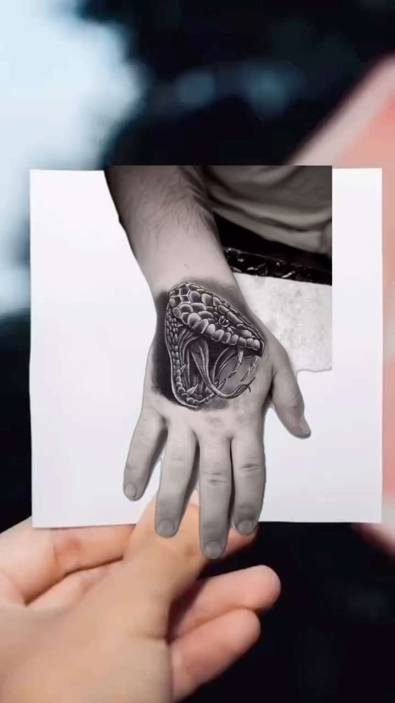 Black and grey realistic snake head tattoo on hand