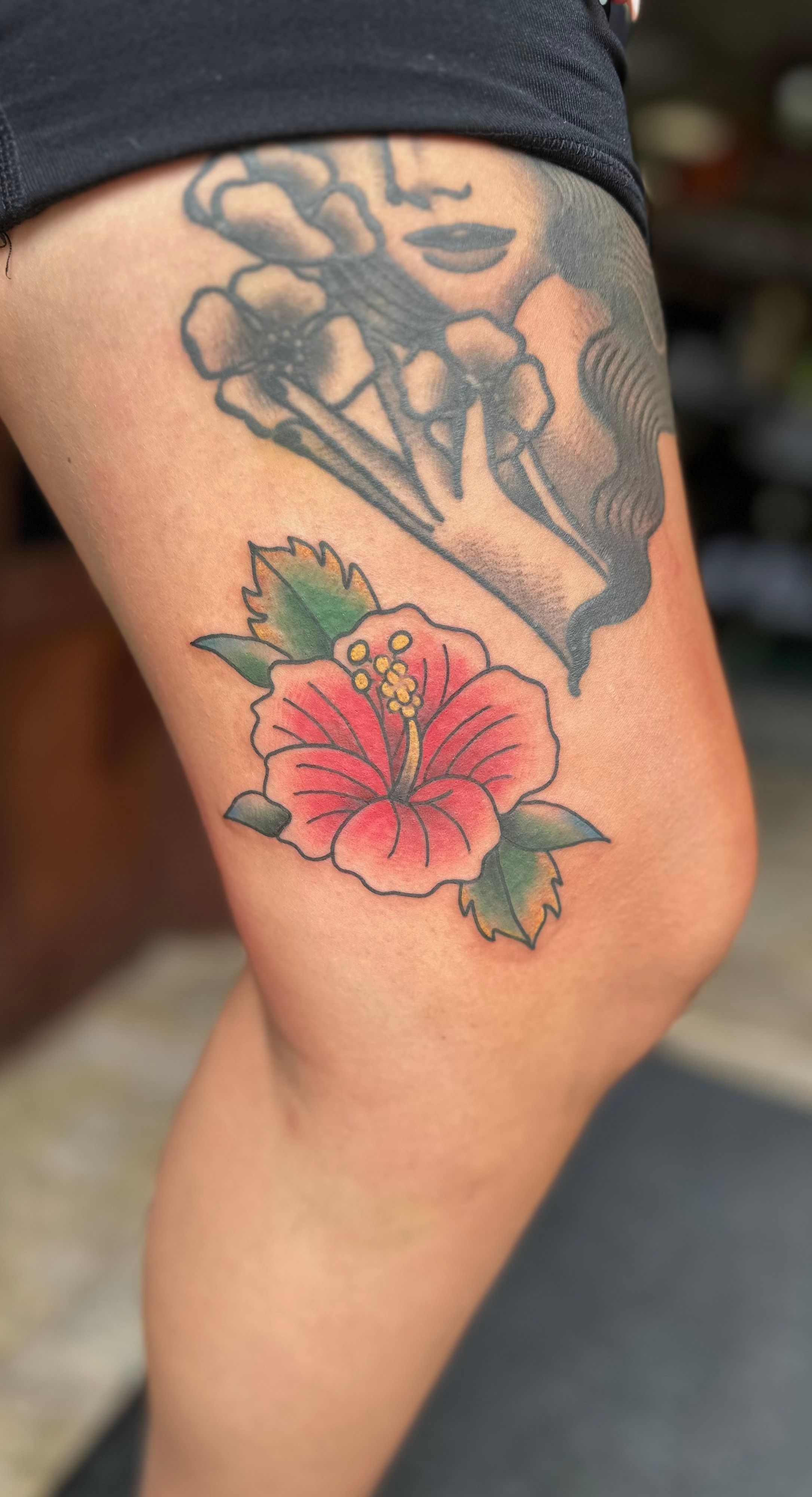 Colorful traditional hibiscus tattoo on the thigh