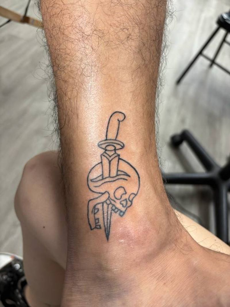 minimalist dagger and skull tattoo on calf