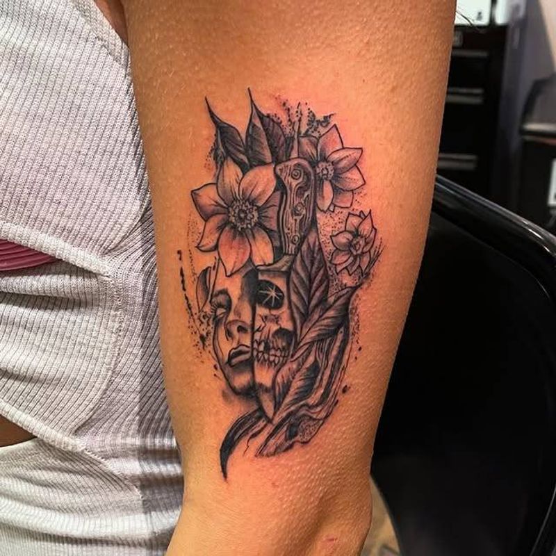 Black and grey illustrative floral and skull tattoo on upper arm