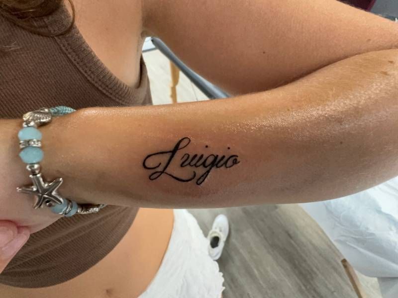 script tattoo reading 'Luigio' on forearm