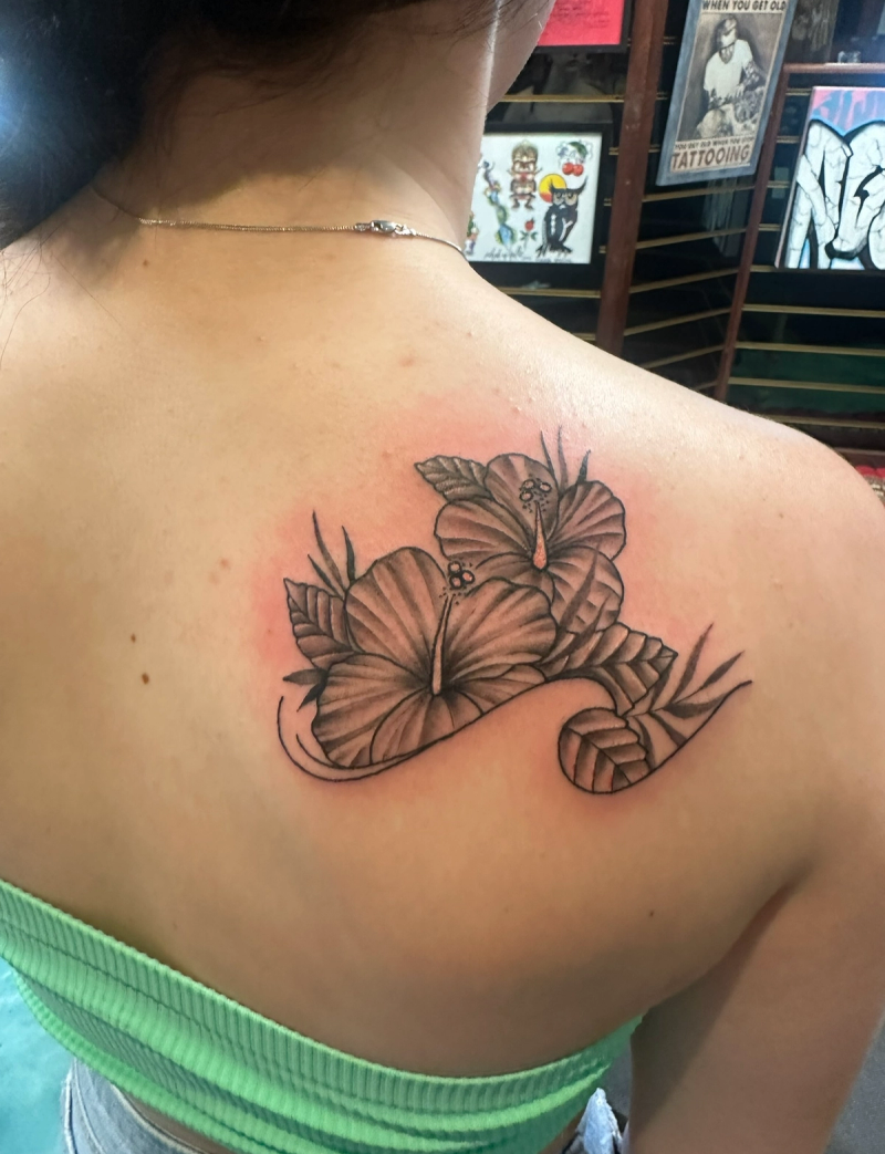 Black and grey hibiscus tattoo on upper back
