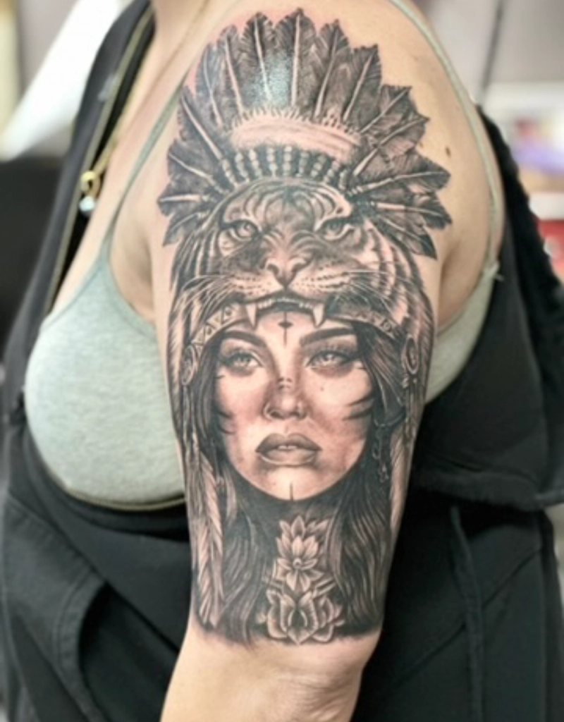 Black and grey realistic portrait and headdress tattoo on upper arm
