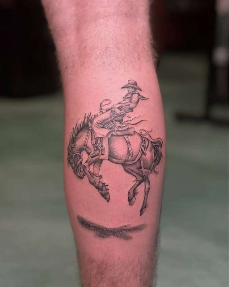 Black and grey realistic cowboy on horse tattoo on calf