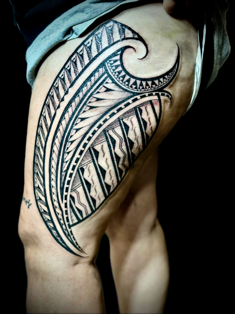 Black and grey tribal tattoo on thigh