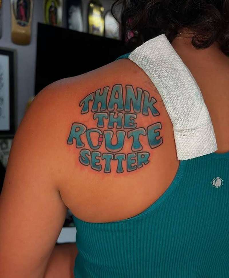Colorful lettering tattoo saying 'Thank the Route Setter' on shoulder