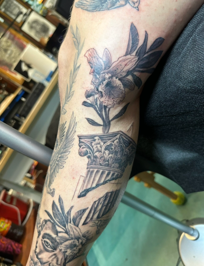 Black and grey illustrative floral and architectural tattoo on forearm