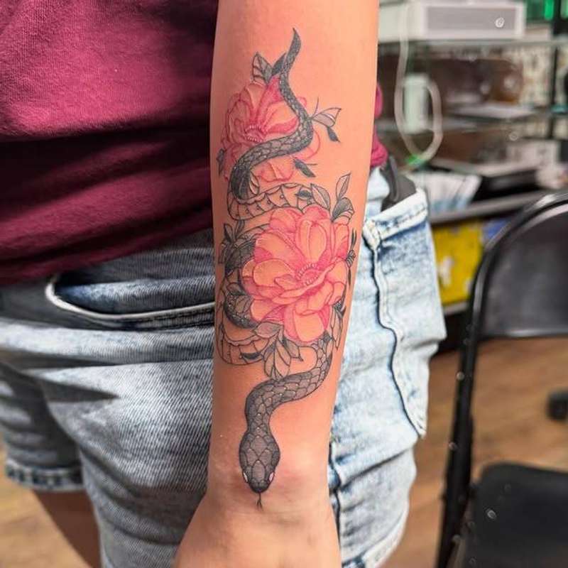 Colorful snake entwined with flowers on forearm