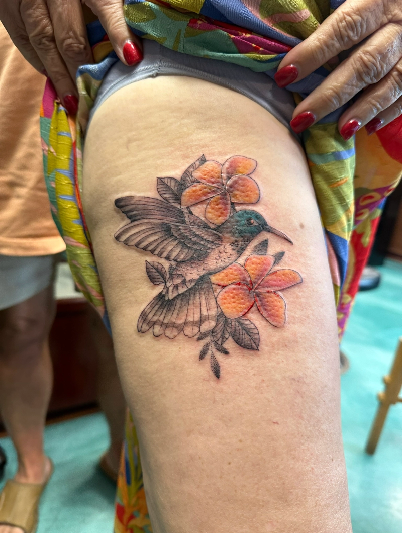 Colorful realistic hummingbird with flowers on thigh
