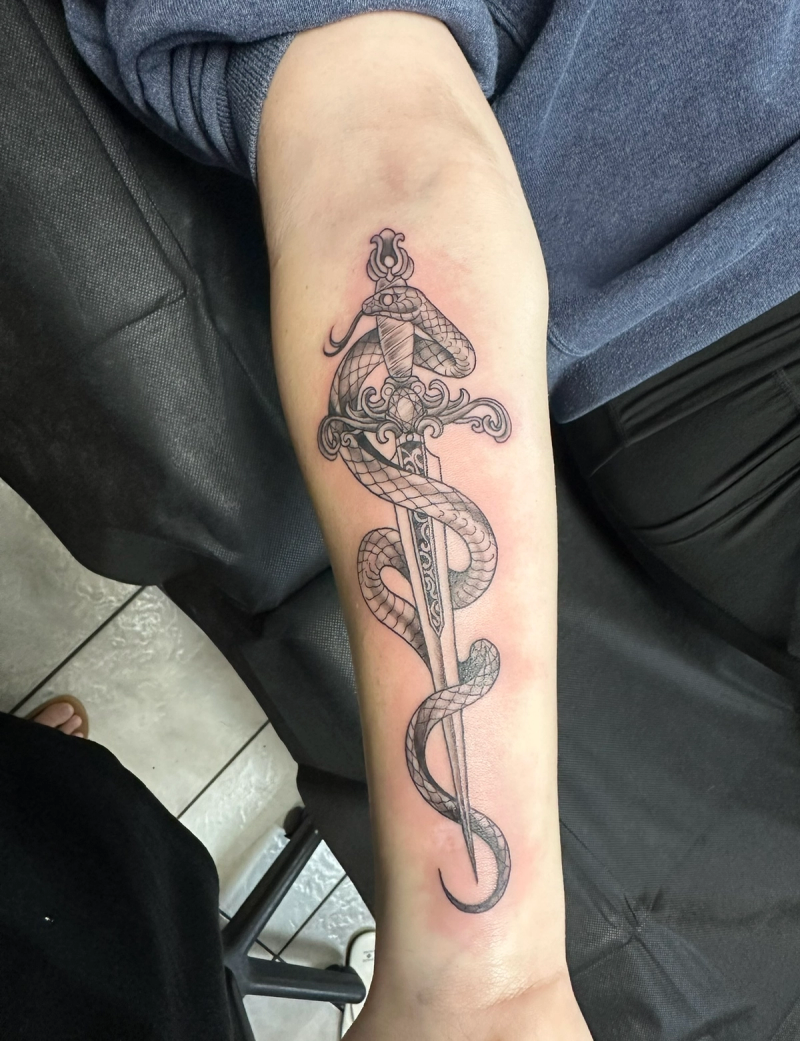 Black and grey sword and snake tattoo on forearm