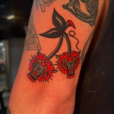 upper arm tattoo of two red tiger heads with black leaves