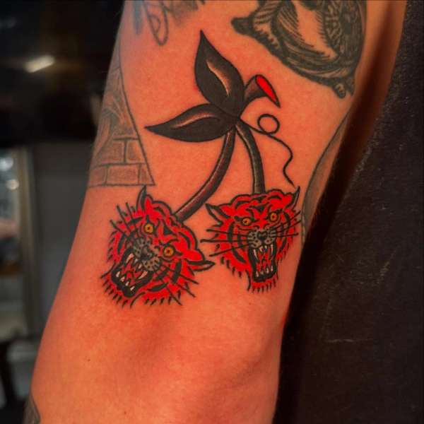 upper arm tattoo of two red tiger heads with black leaves