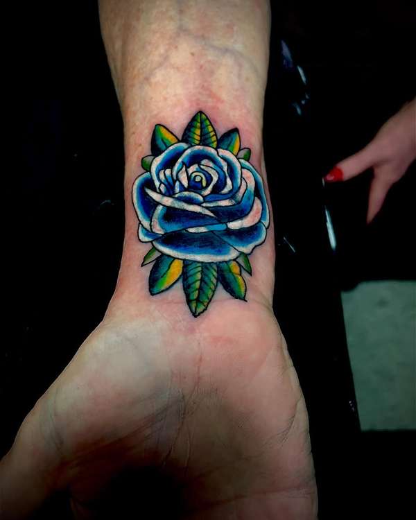 Colorful traditional rose tattoo on wrist