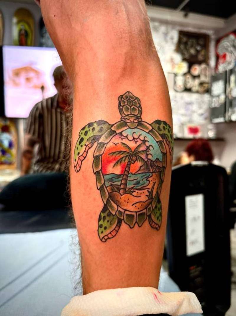 colorful turtle tattoo with beach scene on forearm