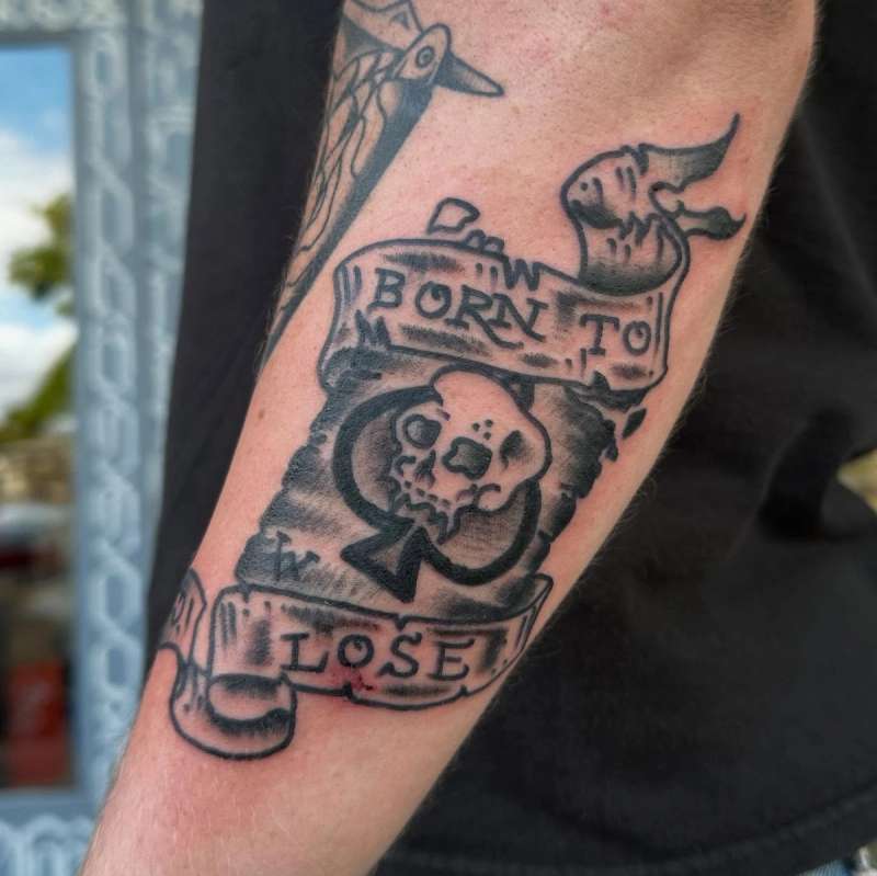 black and grey skull with banner tattoo on forearm