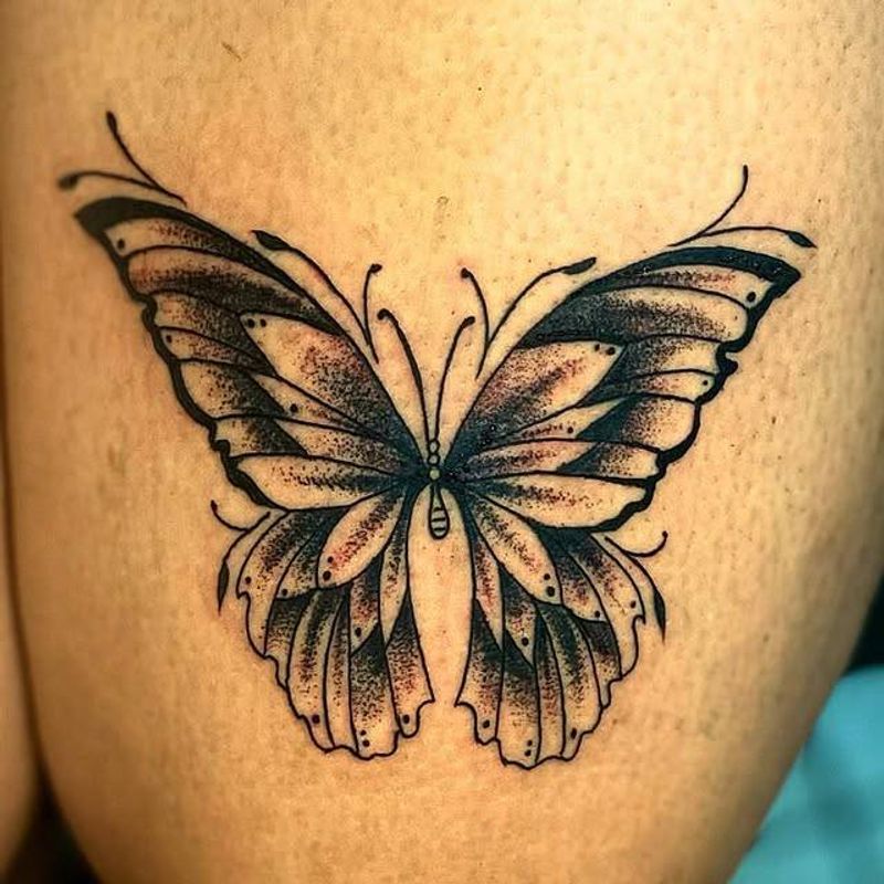 Black and grey illustrative butterfly tattoo on the thigh.
