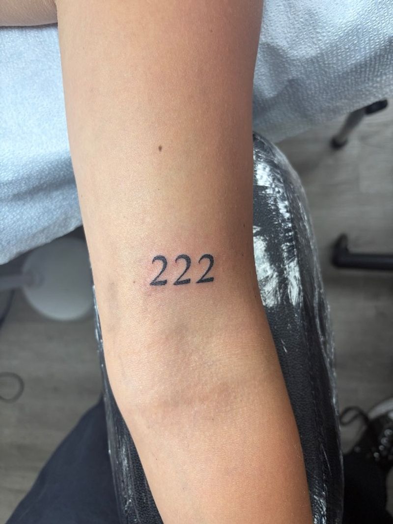 number 222 tattoo on forearm