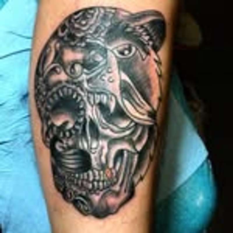Black and grey illustrative dual mask tattoo on upper arm