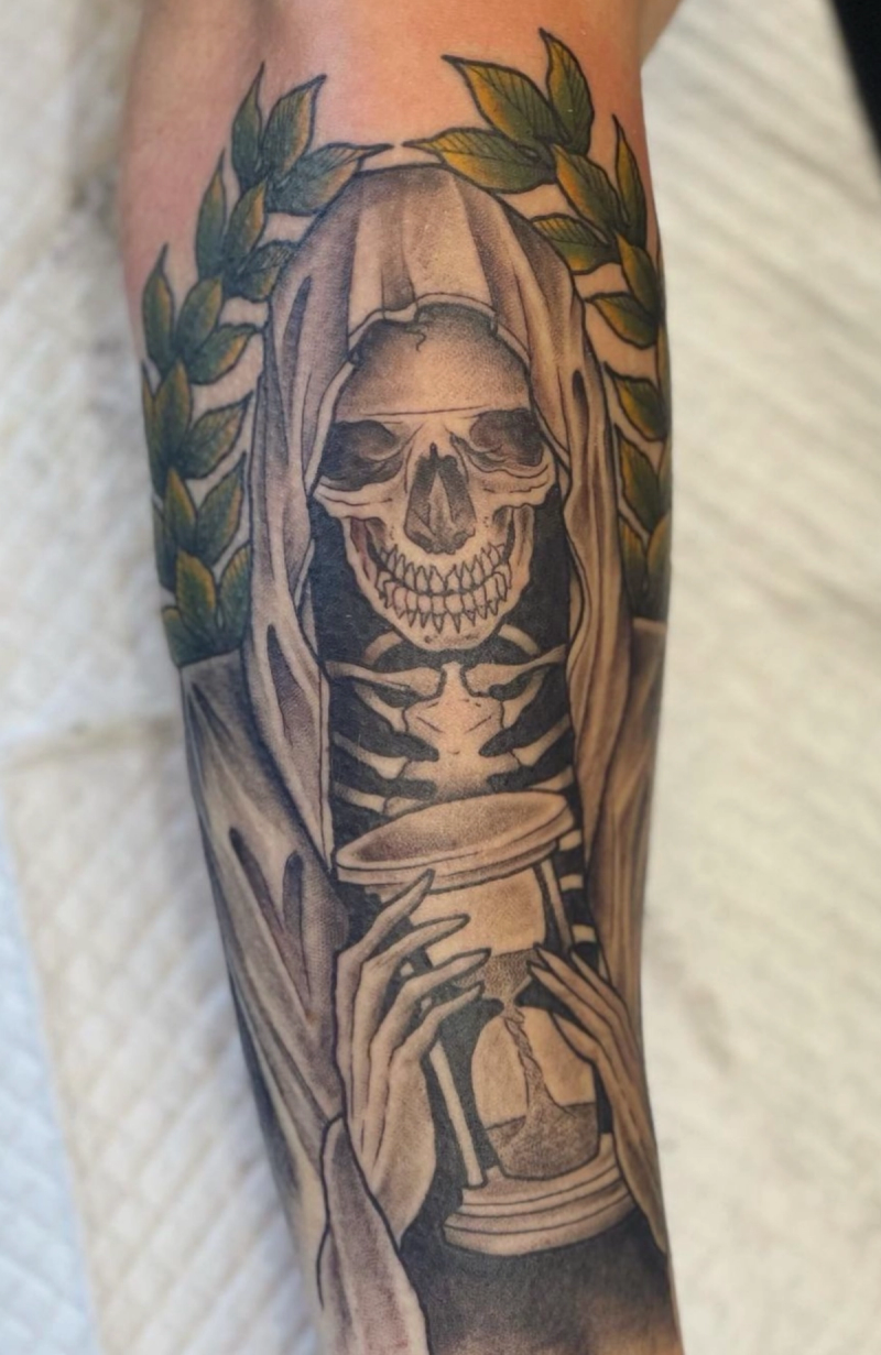 Black and grey illustrative skeleton with hourglass on forearm