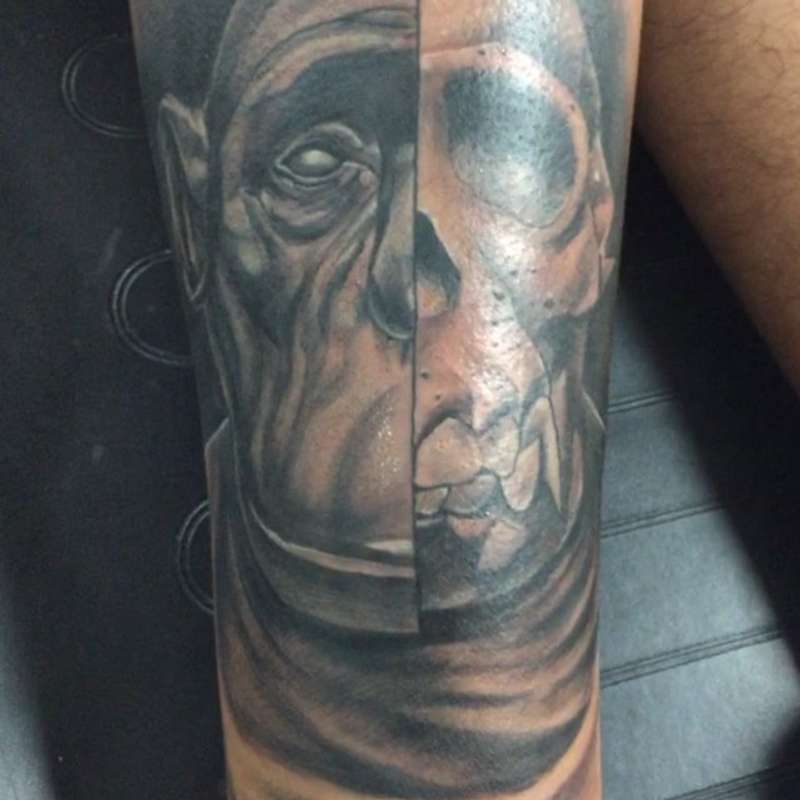 Black and grey realistic face and skull tattoo on forearm