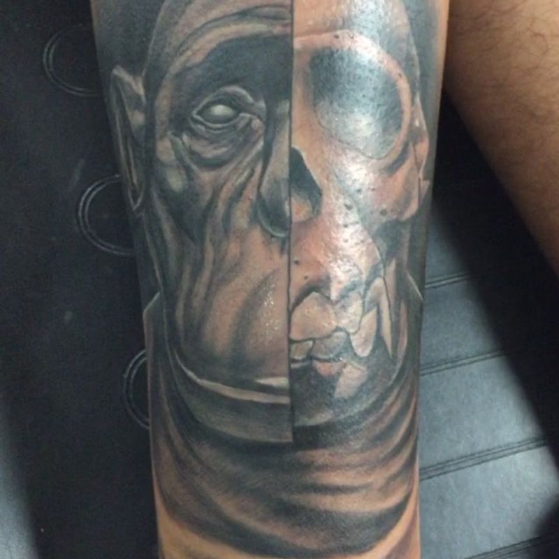 Black and grey realistic face and skull tattoo on forearm