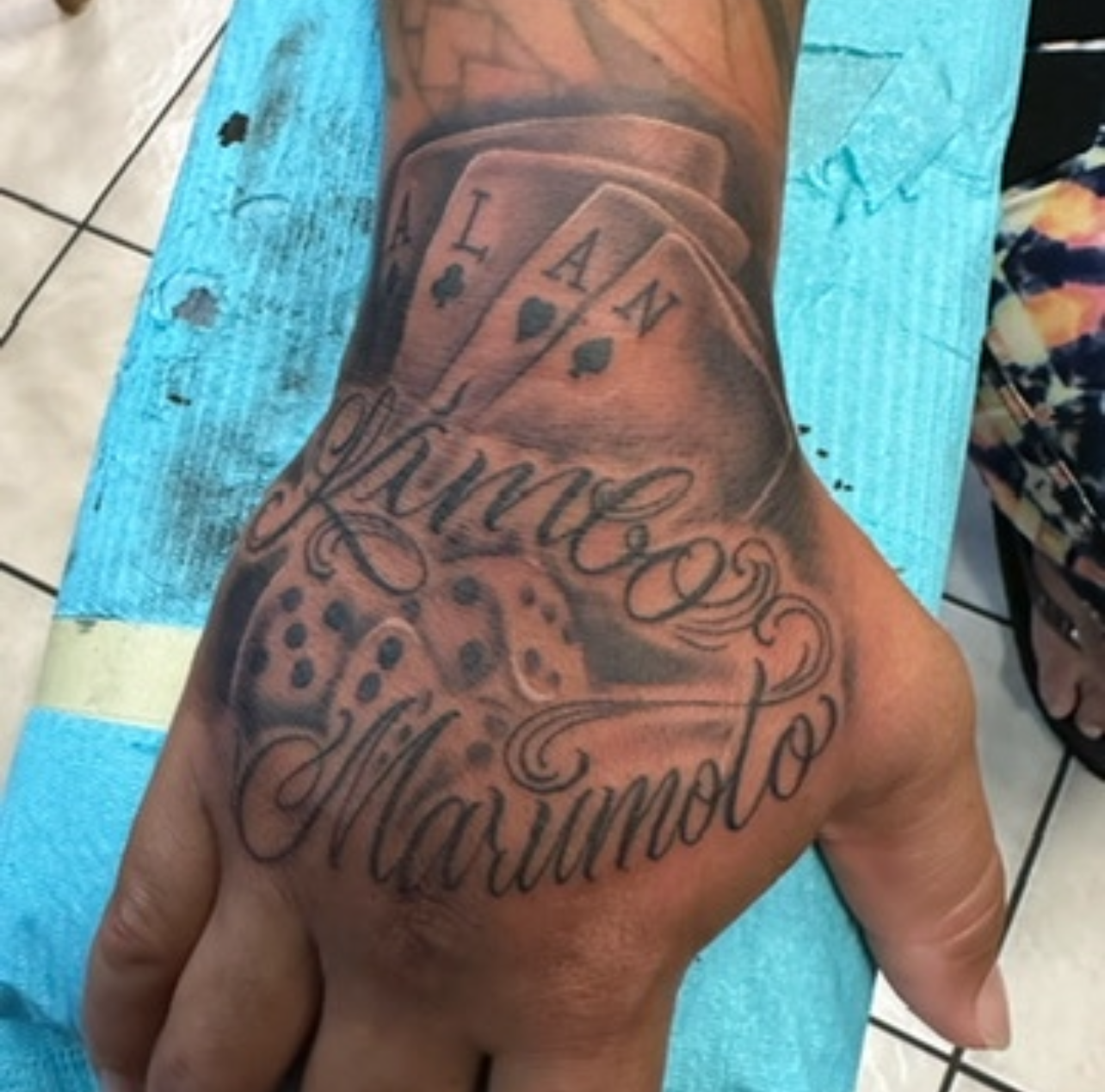 Black and grey realistic playing cards and dice tattoo on hand