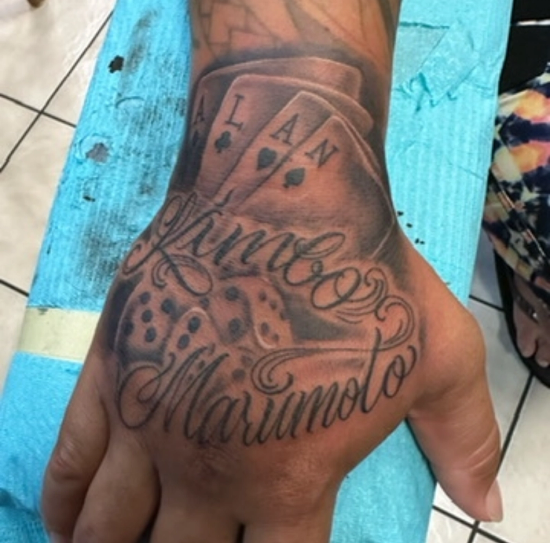 Black and grey realistic playing cards and dice tattoo on hand