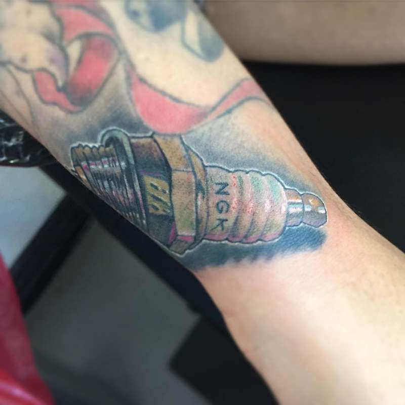 illustrative spark plug tattoo on forearm