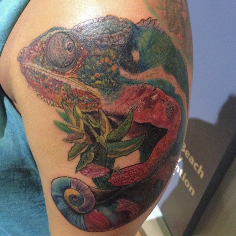 a colorful chameleon tattoo on an upper arm