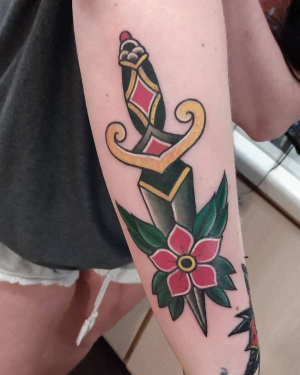 vibrant dagger and flower tattoo on forearm