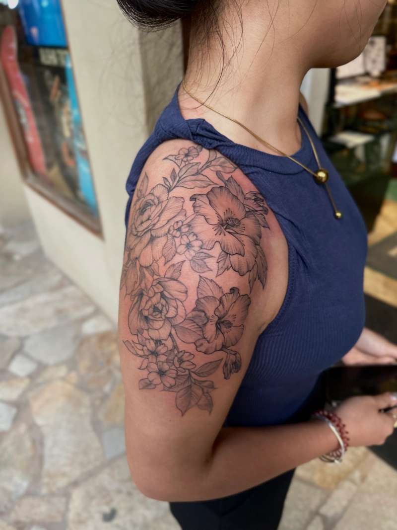 Black and grey floral tattoo on upper arm