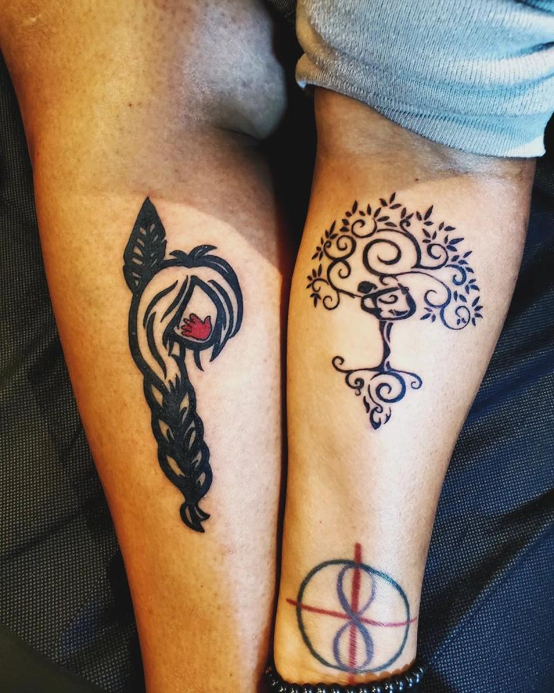 Color illustrative tattoos of abstract tree and braided hair on calf.