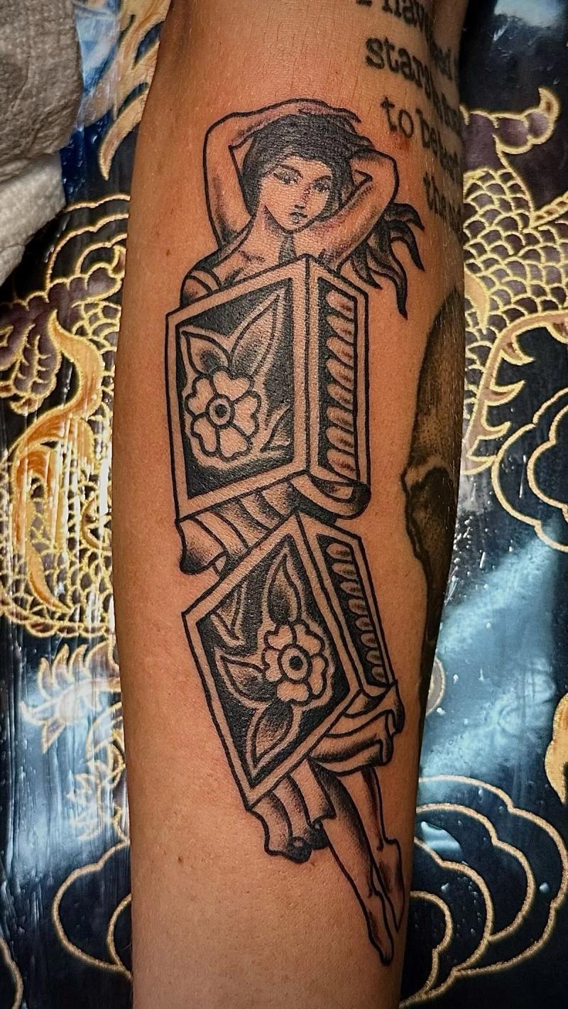 illustrative tattoo of a woman with boxes on forearm