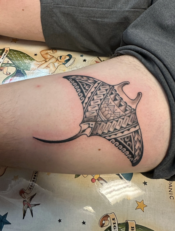 Black and grey tribal manta ray tattoo on thigh