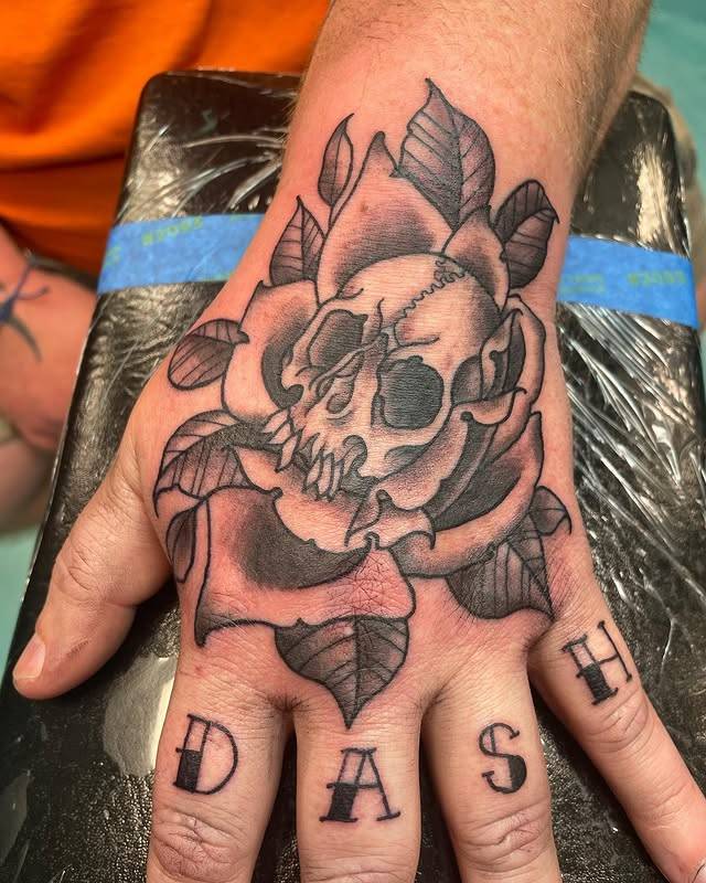Black and grey skull and rose tattoo on hand