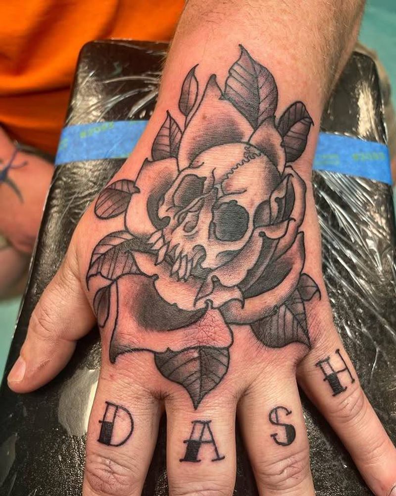 Black and grey skull and rose tattoo on hand