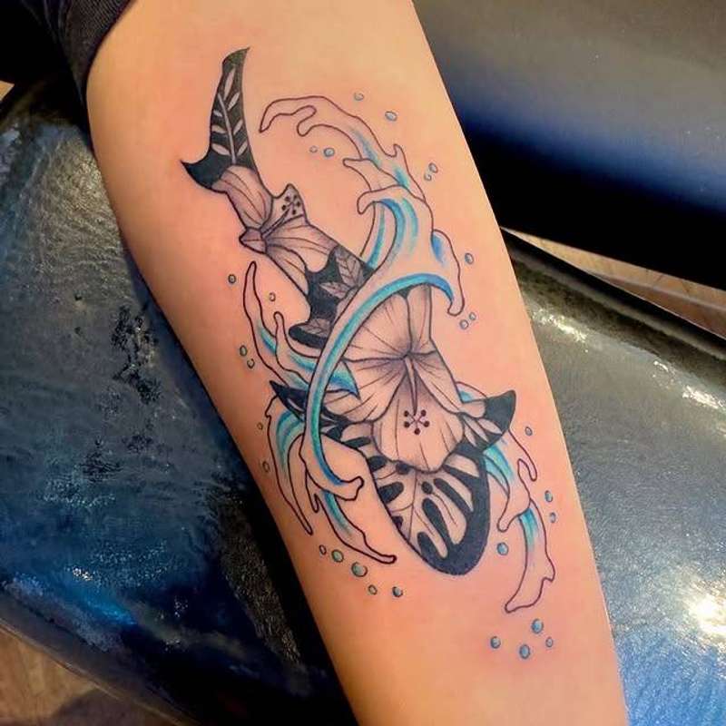 Colorful illustrative sword and flower tattoo on forearm