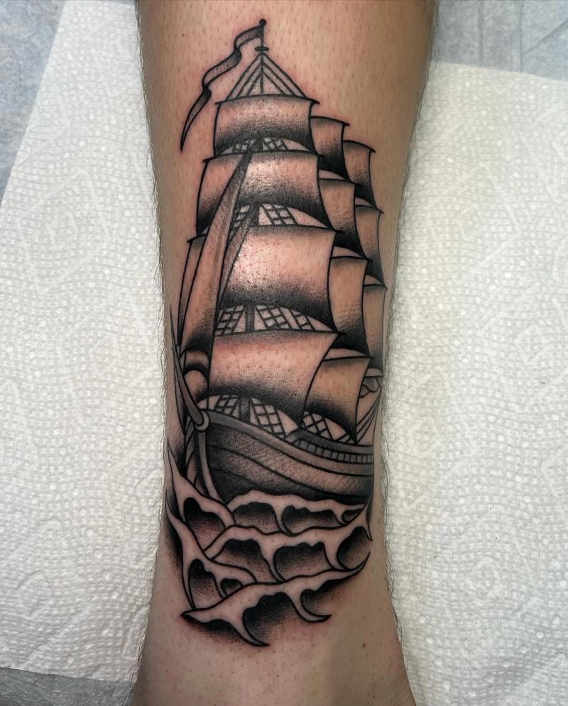Black and grey traditional sailing ship tattoo on calf
