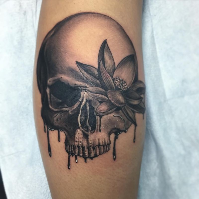 Black and grey skull and flower tattoo on upper arm.