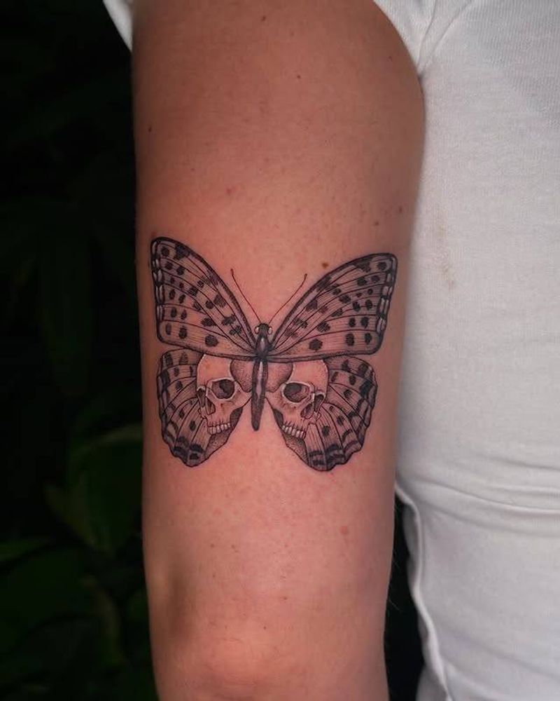 Black and grey illustrative butterfly with skulls on upper arm
