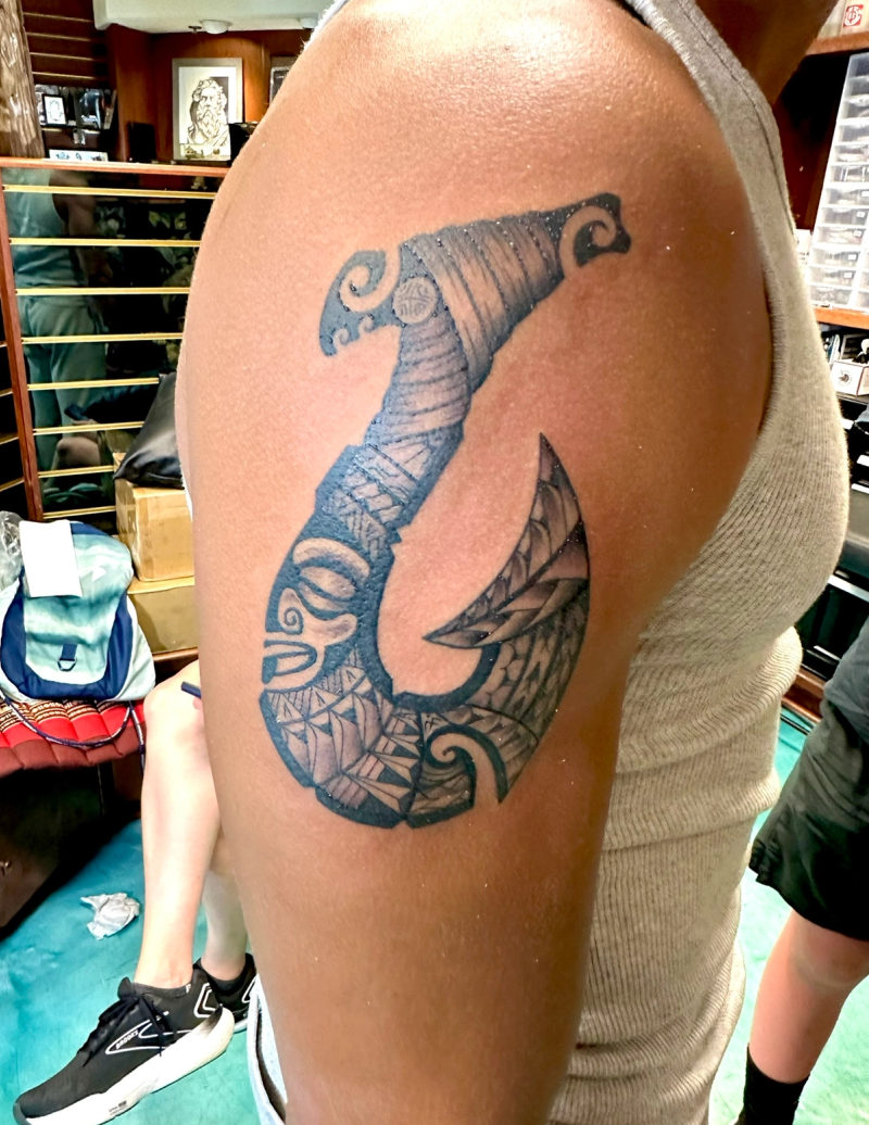Black and grey tribal hook tattoo on upper arm