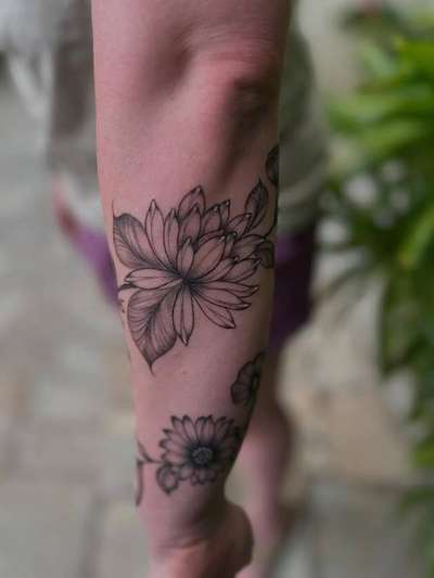 Black and grey fine line floral tattoo on forearm