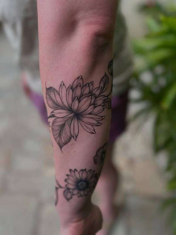 Black and grey fine line floral tattoo on forearm