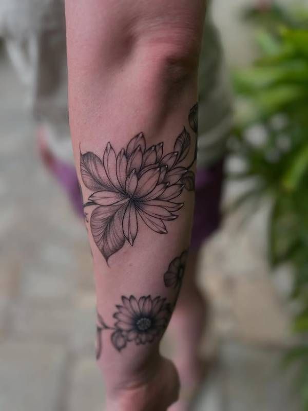 Black and grey fine line floral tattoo on forearm