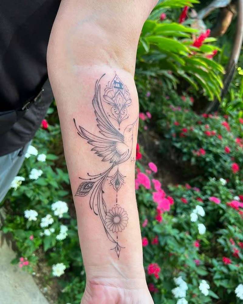 Black and grey fine line hummingbird with floral patterns on forearm
