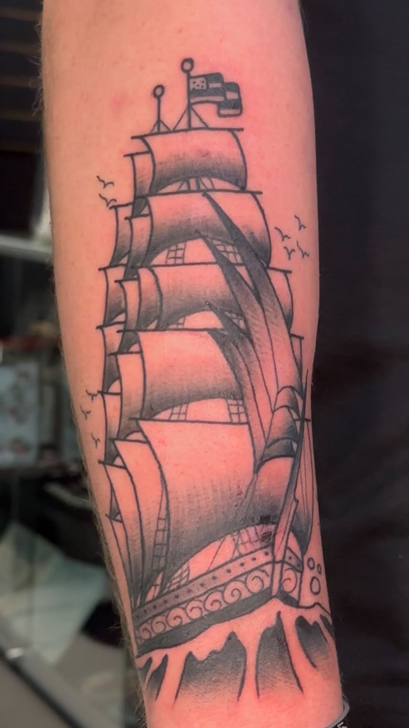 black and grey ship tattoo on forearm