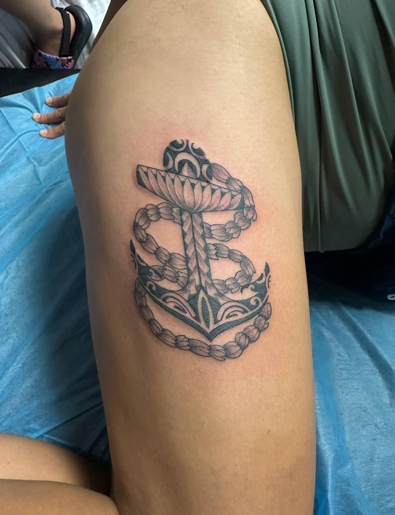 Black and grey tribal anchor tattoo on thigh