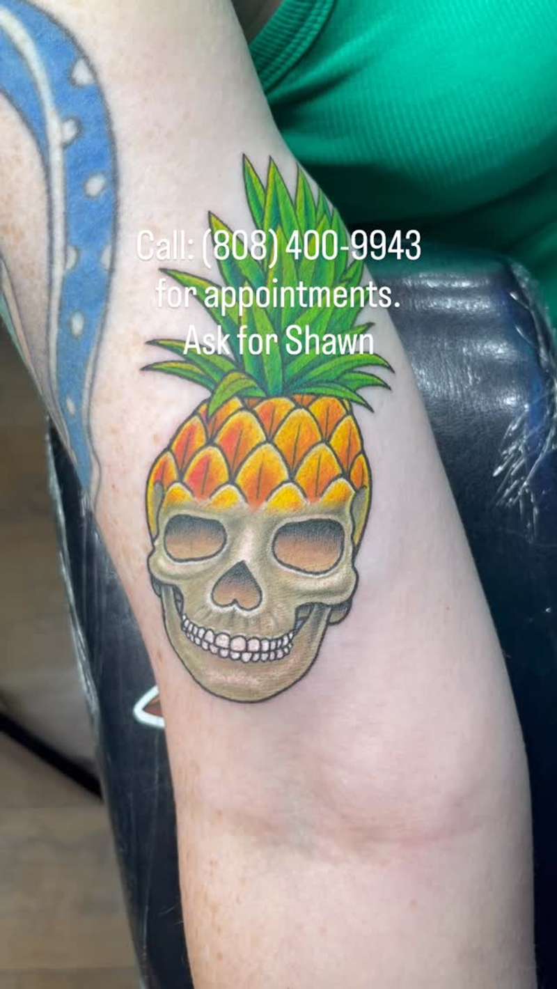 colorful pineapple skull tattoo on upper arm