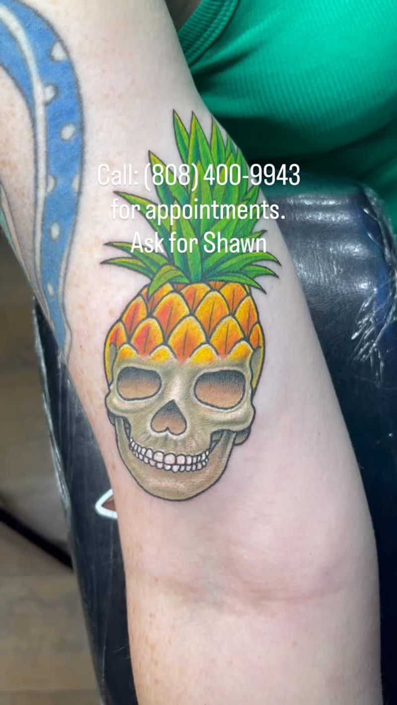 colorful pineapple skull tattoo on upper arm