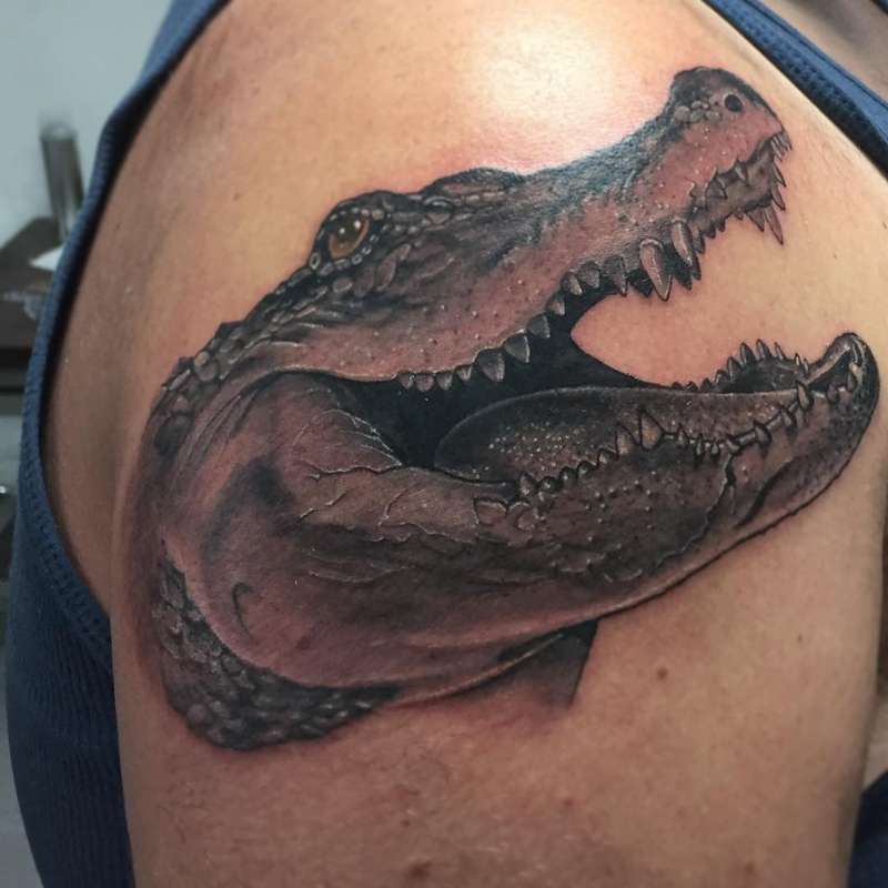 Black and grey realistic crocodile head tattoo on upper arm